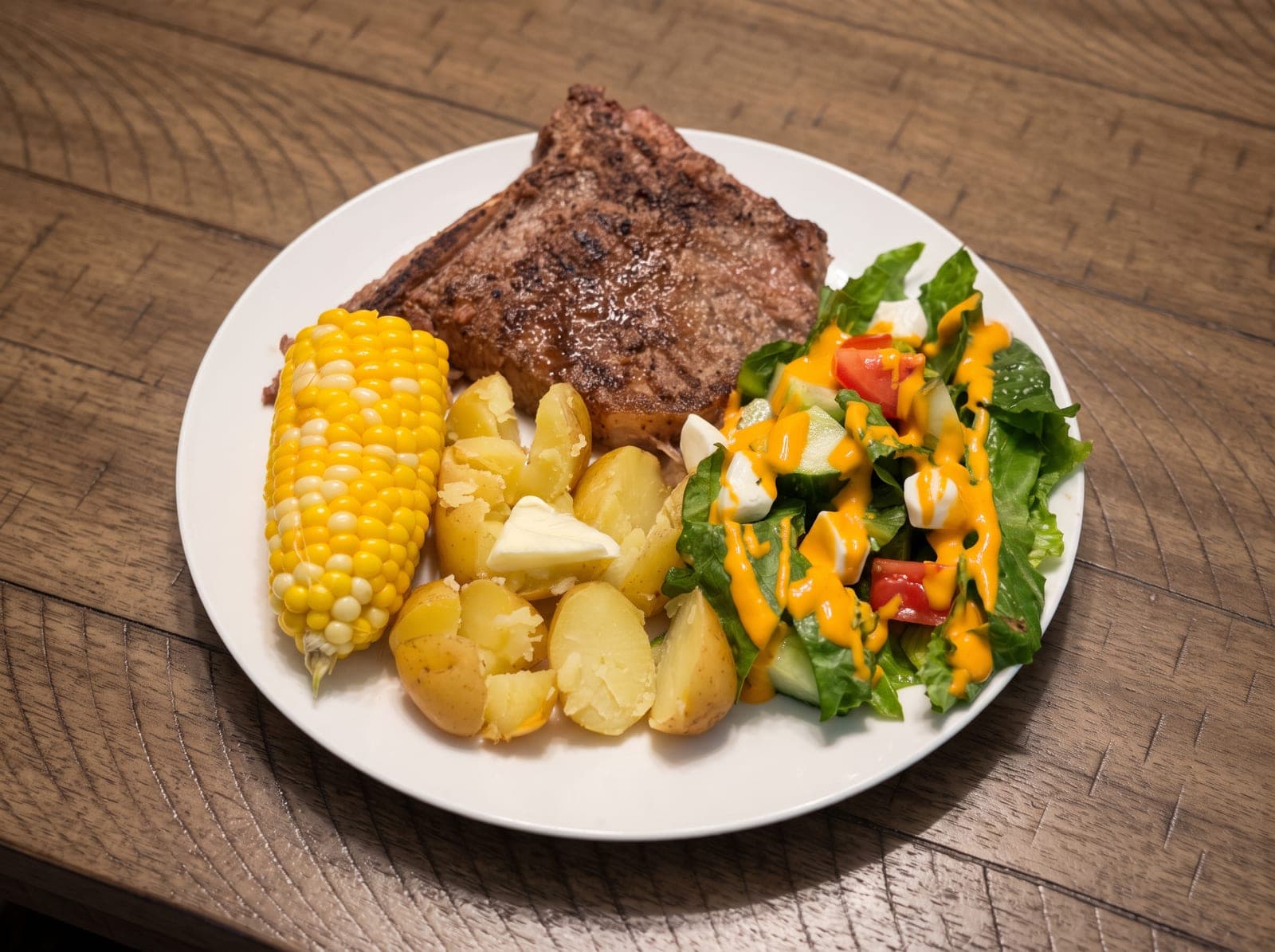 A balanced plate: grilled steak, baby potatoes, corn on the cob and a salad
